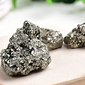 Três amostras de pirite em bruto com superfície brilhante e textura granular, exibindo o seu brilho metálico prateado.
