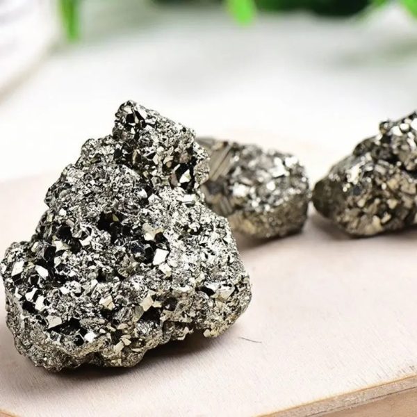 Três amostras de pirite em bruto com superfície brilhante e textura granular, exibindo o seu brilho metálico prateado.