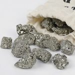 Vários fragmentos de pirite com superfície brilhante e textura granular, alguns a sair de um saco de tecido natural.