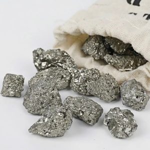 Vários fragmentos de pirite com superfície brilhante e textura granular, alguns a sair de um saco de tecido natural.