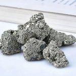 Conjunto de várias pedras de pirite com superfície metálica brilhante e textura granular, exibindo diferentes tamanhos e formas.