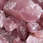 Vários cristais de quartzo rosa em bruto, com superfícies irregulares e cor rosa suave, exibindo textura natural e transparência parcial.