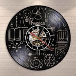 Relógio de parede com design de símbolos e fórmulas de física, incluindo átomos, luz, e instrumentos científicos, em fundo preto com detalhes brancos.