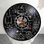Relógio de parede preto com símbolos e fórmulas de física em branco, mostrador analógico com mecanismo visível ao centro, decorativo e educativo.