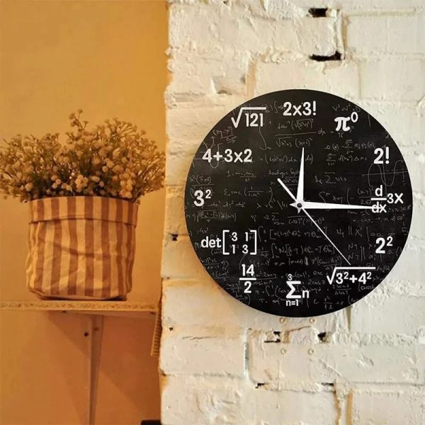 Relógio de parede preto com fórmulas matemáticas e símbolos científicos, mostrando as horas, fixado numa parede de tijolos brancos, ao lado de uma planta em vaso.