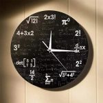 Relógio de parede com fundo preto e equações matemáticas brancas, mostrando horas e minutos, com ponteiros brancos.