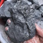 Pedra de shungite bruta com superfície irregular e cor escura, destacando-se pela textura áspera e aspecto natural.