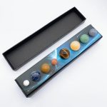 Conjunto de pedras preciosas representando os planetas do Sistema Solar, com nomes e cores distintas, em caixa de apresentação.