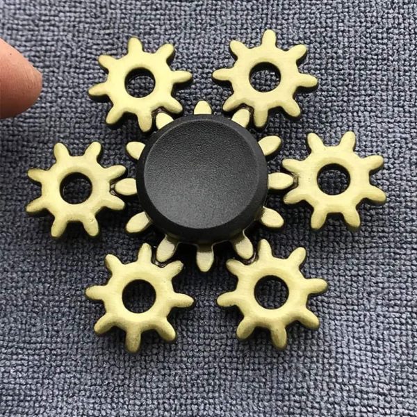 Conjunto de engrenagens de plástico amarelas com um centro preto, usado como spinner de mão, sobre uma superfície texturizada cinzenta.