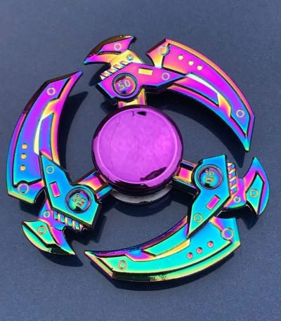 Spinner de mão com lâminas metálicas iridescentes, cada lâmina com detalhes coloridos e números, sobre fundo escuro.