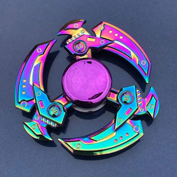 Spinner de mão com lâminas metálicas iridescentes, cada lâmina com detalhes coloridos e números, sobre fundo escuro.