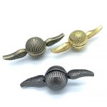 Três spinners de mão com asas, dois dourados e um prateado, vistos de diferentes ângulos, com detalhes em relevo e acabamento metálico.