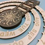 Calendário perpétuo de parede com roda de meses, dias e uma peça decorativa com sol e estrelas, feito de madeira gravada.