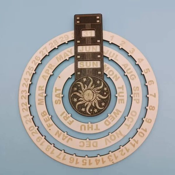 Calendário perpétuo de parede com disco de madeira, mostrando o mês, dia e data, decorado com símbolo do sol e lua, em tons naturais.
