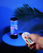 Lâmpada de plasma com efeito de relâmpagos coloridos, controlada por um comando remoto, colocada numa mesa junto a uma folha de palmeira.