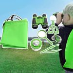 Conjunto de brinquedos de exploração com binóculos, lupa, escova, tesoura, e saco verde, usado por uma criança ao ar livre.