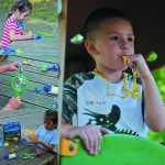 Criança a brincar com um kit de insetos ao ar livre, usando uma lupa e ferramentas de observação, com outros brinquedos no chão.