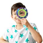 Criança segura uma lupa colorida com tema de espaço, com estrelas e planetas, para explorar objetos pequenos.