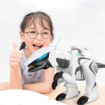 Criança sorridente com óculos, mostrando polegares, ao lado de um robô dinossauro branco com detalhes pretos e luzes azuis, em fundo branco.