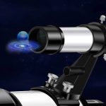 Telescópio com corpo metálico e suporte ajustável, apontando para o céu estrelado com uma ilustração de planeta e órbita.