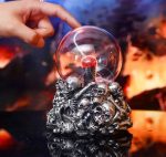 Bola de plasma com efeito de relâmpagos dentro de uma caveira de metal detalhada, com fundo escuro e luzes vibrantes.