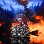 Bola de plasma com design de caveira, luzes coloridas e detalhes escuros, em ambiente com fundo de floresta sombria e fogo.