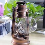 Candeeiro a óleo antigo com vidro inclinado, detalhes metálicos escuros e alça lateral, decorativo e funcional.