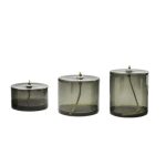 Três candeeiros a óleo cilíndricos de diferentes tamanhos, com tubos de metal e vidro escuro, usados para iluminação decorativa ou científica.