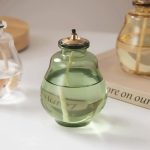 Candeeiro a óleo de vidro verde com tampa metálica, mecha visível e reservatório de óleo transparente, decorativo e funcional.