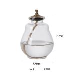 Frasco de vidro com óleo e pavio, altura de 7,7cm, diâmetro de 5,9cm, peso de 52g, capacidade de 100ml, usado em experiências de ciência e iluminação.
