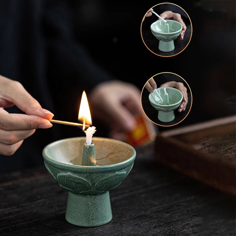 Candeeiro a óleo de cerâmica com chama acesa Pessoa acende uma vela de cera numa base de cerâmica verde, com detalhes decorativos, enquanto outra pessoa segura uma tigela de cerâmica com uma vela acesa.