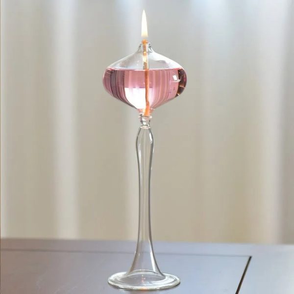 Candeeiro a óleo de pé com base de vidro transparente, vela acesa e recipiente rosa, decorativo e funcional.