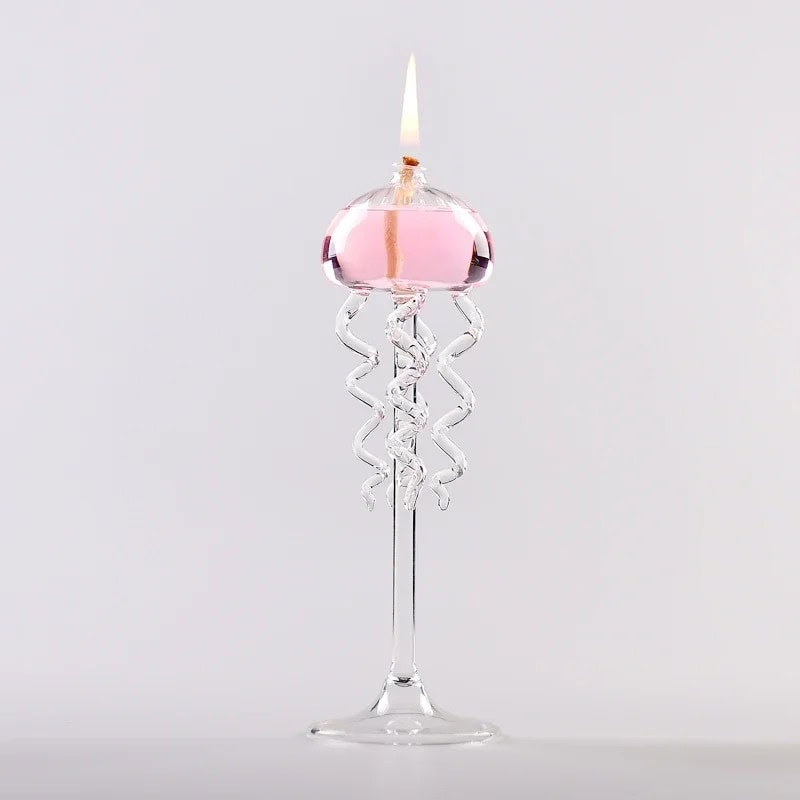 Candeeiro a Óleo Medusas Candeeiro a óleo com design de medusas em vidro transparente, com chama acesa, colocado sobre uma base de vidro.