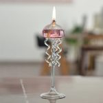 Candeeiro a óleo com design de medusas de vidro, com chamas acesas, colocado numa mesa de sala de estar.
