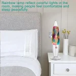 Lâmpada de plasma com luzes coloridas refletindo no quarto, ao lado de um vaso com flores artificiais e uma mesa de cabeceira branca.