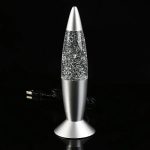 Candeeiro de lava em forma de foguetão com base metálica e corpo transparente cheio de glitter, ligado a um cabo de energia.