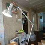 Candeeiro de mesa com braço metálico ajustável, iluminação direcionável, em ambiente de sala de estar com decoração moderna.