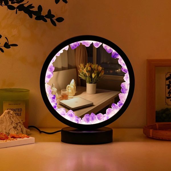 Candeeiro de mesa com luz de cristais roxos e base preta, refletindo uma sala com flores e objetos decorativos ao fundo.