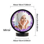 Espelho de mesa com moldura de ametista roxa, refletindo uma mulher sorridente com toalha na cabeça, dimensões aproximadas 18cm de diâmetro e 10cm de altura.