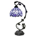 Candeeiro de mesa com abajur de vidro azul e base de metal escuro, com braço ajustável e detalhes decorativos em forma de folhas.