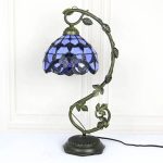 Candeeiro de mesa com base preta, haste decorativa com folhas e lâmpada Tiffany azul com padrão de mosaico.