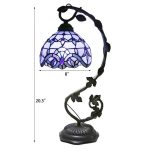 Candeeiro de mesa com abajur em vidro colorido azul e base de metal escuro, com detalhes decorativos florais.
