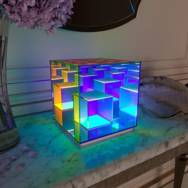 Luminária de mesa com cubos de acrílico iluminados em várias cores, criando efeito de luzes vibrantes e ambiente moderno.