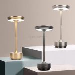 Três candeeiros de mesa em diferentes cores: dourado, cinza escuro e prateado, com design moderno e base sólida, colocados em plataformas de diferentes alturas.