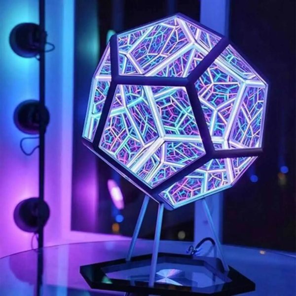 Luminária de mesa com estrutura geométrica iluminada por LEDs coloridos, com padrão de linhas e formas modernas, em ambiente escuro.
