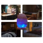 Lâmpada de sal com luz azul acesa, colocada numa mesa de quarto, com ambiente acolhedor e decoração de madeira ao fundo.