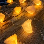 Luzes decorativas com pedras de sal amareladas em fio de luzes, criam ambiente acolhedor e relaxante.