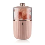 Açucareiro portátil com recipiente transparente contendo sal grosso rosa, base rosa com ranhuras verticais, tampa dourada com botão de pressão.