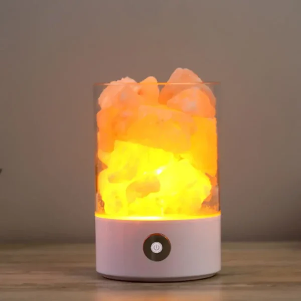 Lâmpada de plasma com nuvem de cores laranja e amarela, iluminação interna brilhante, base branca com botão de energia, sobre superfície de madeira.