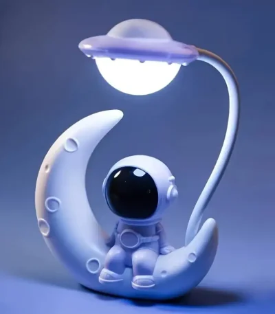 Luminária decorativa de astronauta sentado na lua com lâmpada em forma de estrela acima, iluminação suave e ambiente de espaço.
